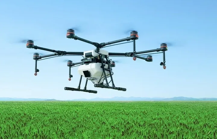 Dron agrícola de fumigación sobrevolando un campo de cultivo